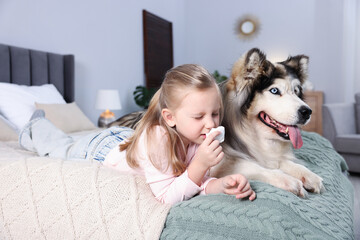 Girl suffering from allergy with her dog on bed at home
