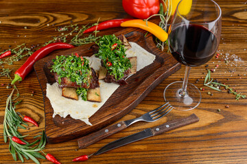 braised pork ribs with herbs on a wooden board on a wooden background with decor and wine