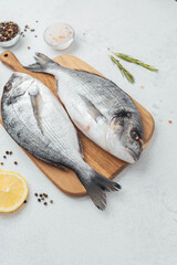 Close up of dorado fish tomatoes lemon and spices on cutting board