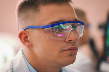 Young man wearing glasses with reflection on blurred background, closeup