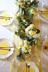 Top view of an elegant lemon-themed table setting with floral arrangements and citrus slices on...