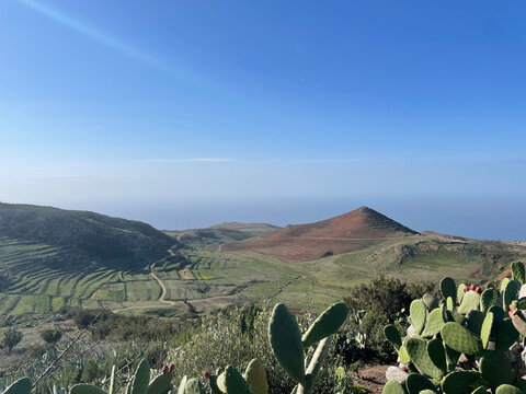 Mountain Hike in Tenerife with Brown Hill and Ocean Horizon, Peaceful Landscape with Green Vegetation in the Foreground and Blue Sea in the Distance, Capturing the Island&rsquo;s Natural Contrast