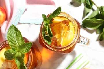 Refreshing iced peach tea with mint in mason jars on table, flat lay