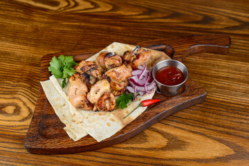 fried chicken kebab in pita bread with onions and herbs on a wooden board