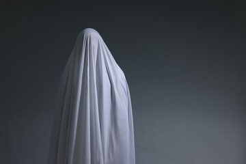 Creepy ghost. Man covered with white sheet on light grey background, space for text