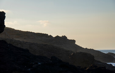 Jagged basalt cliff at dawn above calm muted ocean.