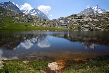 Reflections on lac Perrin inferieur (Perrin lower lake) located above Petit Mont Cenis Pass (near Mont Cenis lake), Maurienne Valley, Savoie, Northern French Alps, France, surrounded by mountains