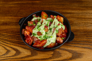 Potato fries in tomato sauce with cheese in a frying pan on the background