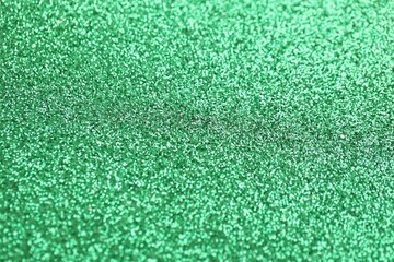 Beautiful green glitter sparks texture as background with shallow depth of field