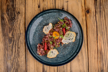 Beef tartare on a plate with croutons and pepper
