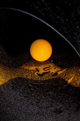 Abstract image with orange ball and water drops on reflective surface