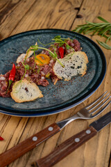 Beef tartare in a blue plate with croutons and pepper