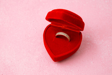 Paved diamond ring in heart-shaped red box on pink background