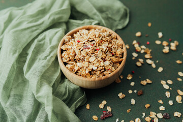 Top view granola bowl with scattered oats and green textile