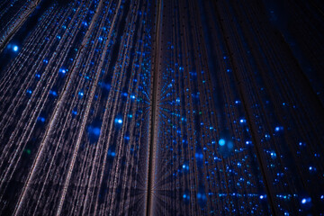 Futuristic room filled with long vertical hanging lights suspended in all directions, creating a dazzling immersive light experience.
