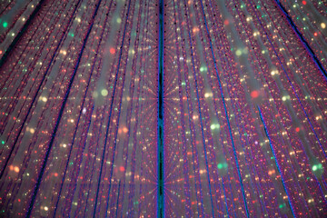 Futuristic room filled with long vertical hanging lights suspended in all directions, creating a...