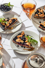 A slice of homemade blueberry crumble pie on a plate on white tile background. Sweet breakfast...