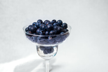 Fresh blueberries displayed in a glass bowl on a light background