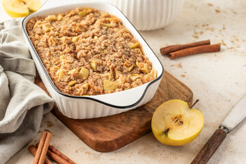 Apple pie baked oatmeal in baking dish on kitchen table background