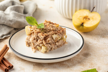 Slice of apple pie baked oatmeal in a plate on kitchen table background