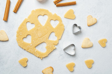 Heart cookies and baking dough on pastel background with cinnamon for romantic, food blog or recipe concept