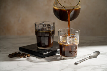 Pouring coffee over glass with ice, making iced coffee drink