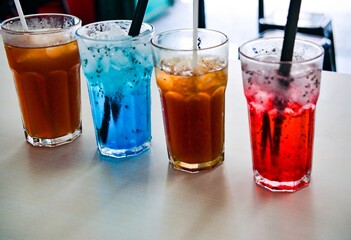 Sweet cold drinks of various flavors and colors in glasses on the table.