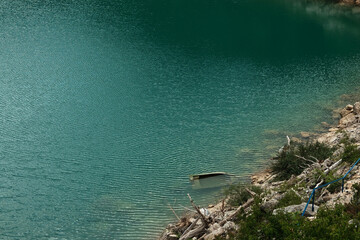 Partially submerged wooden boat and rocky shoreline of Zaovine Lake in Tara National Park, Serbia.