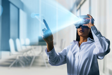 Businesswoman using vr headset interacting with holographic interface in modern office environment with immersive digital projection light.
