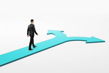 Businessman walking toward a split road with arrows pointing left and right on a light gradient...