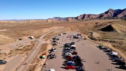 Fruita, United States - 28 July 2025: Aerial view of parked cars and event setup contrasting with the arid landscape under a clear blue sky.