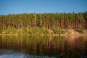 Picturesque landscape with river and forest at first sunbeams of sunset.