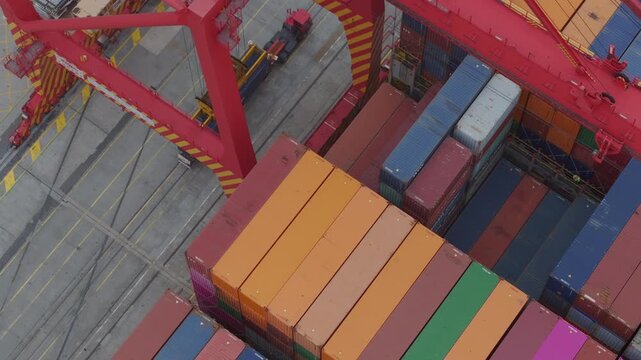 Fremantle, Australia - 27 July 2025: Aerial view of a port scene where a red crane lifts blue container, contrasting against the colorful cargo containers.
