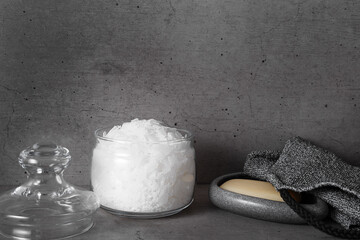 Natural magnesium salt in glass jar, soap, exfoliating loofah, gray bathroom, concrete background....
