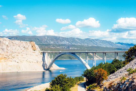 Arched concrete bridge on the backdrop of green hills and distant mountains. Krk bridge, Croatia - Powered by Adobe