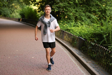 Smiling sportsman in headphones running outdoors. Morning exercise