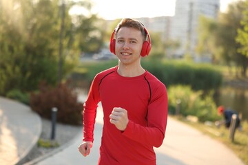 Smiling sportsman in headphones running outdoors. Morning exercise