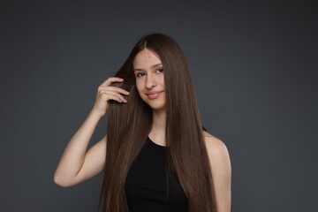 Portrait of beautiful teenage girl with healthy long hair on dark grey background