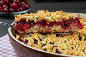 Baking dish with tasty cherry pie, closeup. Delicious homemade pie with fresh red cherries on wooden table. Summer shortcrust pie with berries