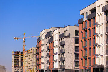 Fototapeta premium Construction of buildings and high-rise cranes against the sky
