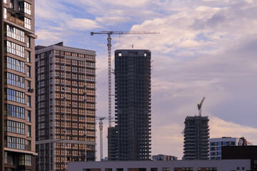 Fototapeta premium Construction of buildings and high-rise cranes against the sky