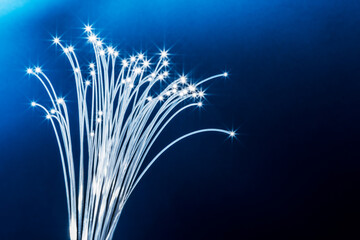 Bundle of optical fibers with lights in the ends. Blue background.