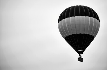 Obraz premium A black and white hot air balloon floating in the sky with a minimalist background