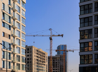 Construction of buildings and high-rise cranes against the blue sky