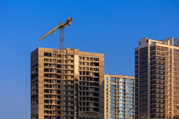 Fototapeta premium Construction of buildings and high-rise cranes against the sky