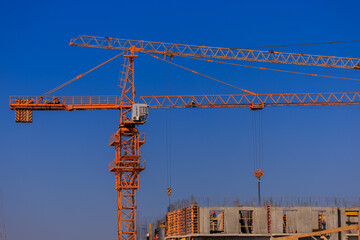 Construction of buildings and high-rise cranes against the blue sky