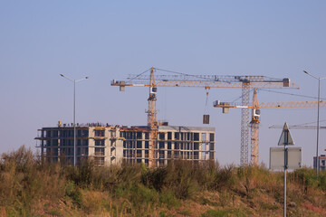 Construction of buildings and high-rise cranes against the blue sky