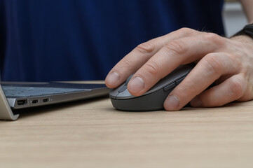 Close-up of a computer mouse, a man's hand is resting on our computer mouse.