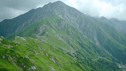 Fototapeta premium Lush green mountain range under a cloudy sky