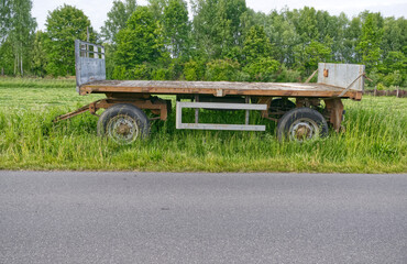 Old wooden trailer standing empty in grassy rural field